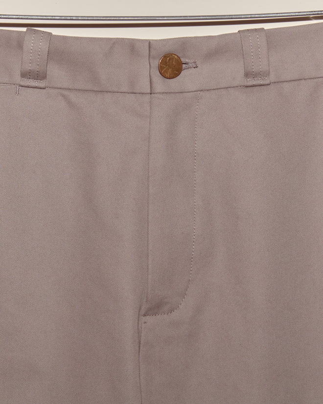Close-up of Campus Trousers - Grey in heavyweight cotton twill, with a button closure and belt loops, hanging on a rod.
