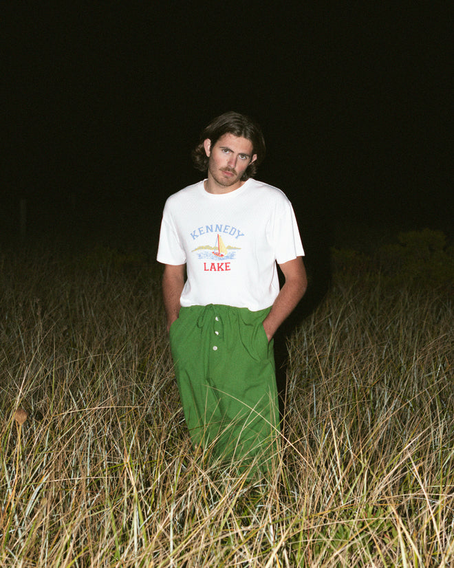 White ribbed cotton short sleeve tee shirt that features a sailboat graphic screenprint with the words 