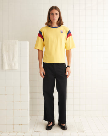 Yellow cotton tee with striped shoulder inserts and three-quarter-length sleeves. The tee feaures mesh bands of red and blue.