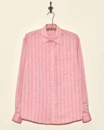 The Carnelian Fletcher Shirt - M, a pink geometric stripe long-sleeve made from deadstock shirting fabric, hangs on a hook against a light background.