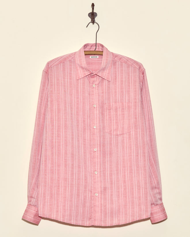 The Carnelian Fletcher Shirt - M, a pink geometric stripe long-sleeve made from deadstock shirting fabric, hangs on a hook against a light background.