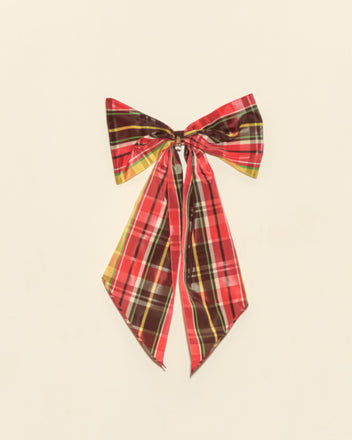 The Carol Bell Bow features a red and yellow vintage plaid ribbon with long tails and a brass bell charm, beautifully displayed on a plain light background.