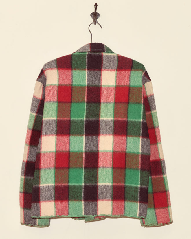 Cedarwood Jacket - XS in red, green, white, and brown plaid wool hangs on a wall hook, viewed from the back—a unique midcentury piece with timeless style.