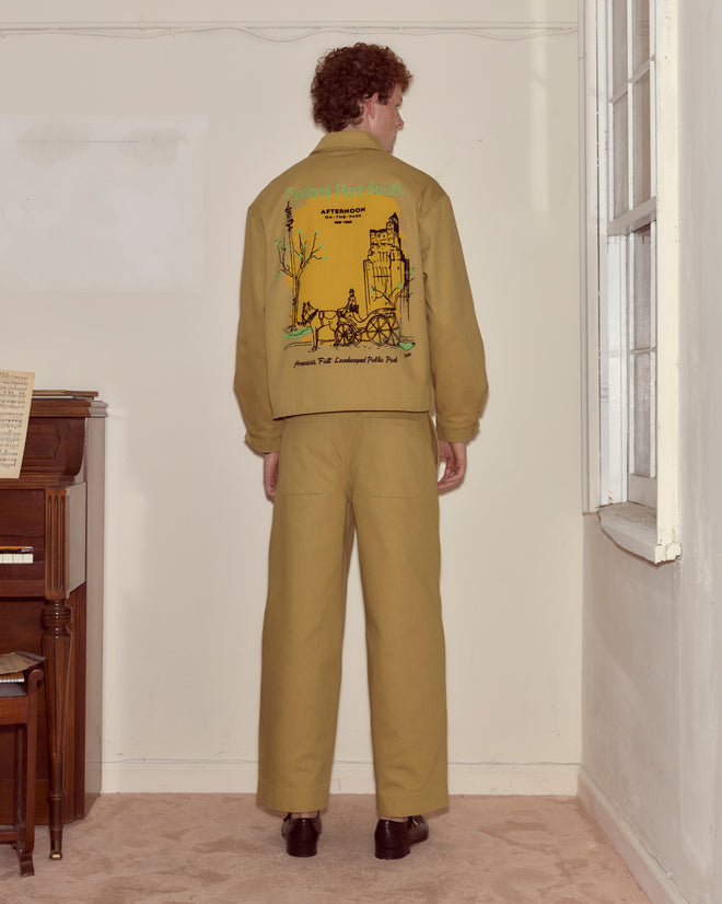 Wearing the Central Park Jacket, a person faces away from the camera in Central Park, showcasing its graphic design.