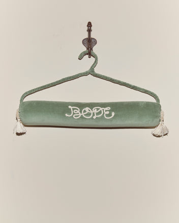 A Cloakroom Hanger - Teal, featuring "HOPE" embroidered in white and finished with tassels at each end, adds a touch of charm when displayed on a wall hook.