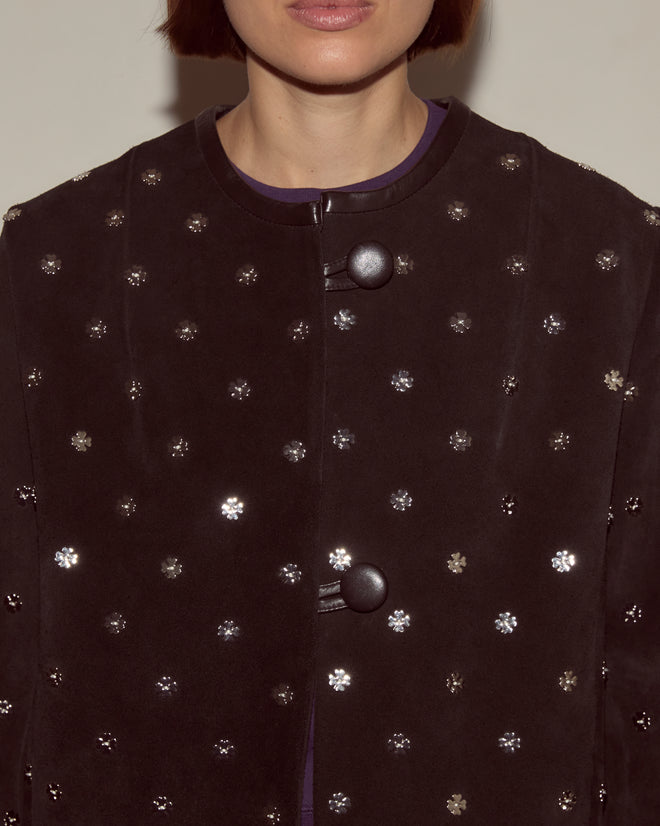 A woman wears the Clover Charm Jacket, a vintage-inspired piece with a boxy silhouette, large buttons, and subtle silver floral accents.