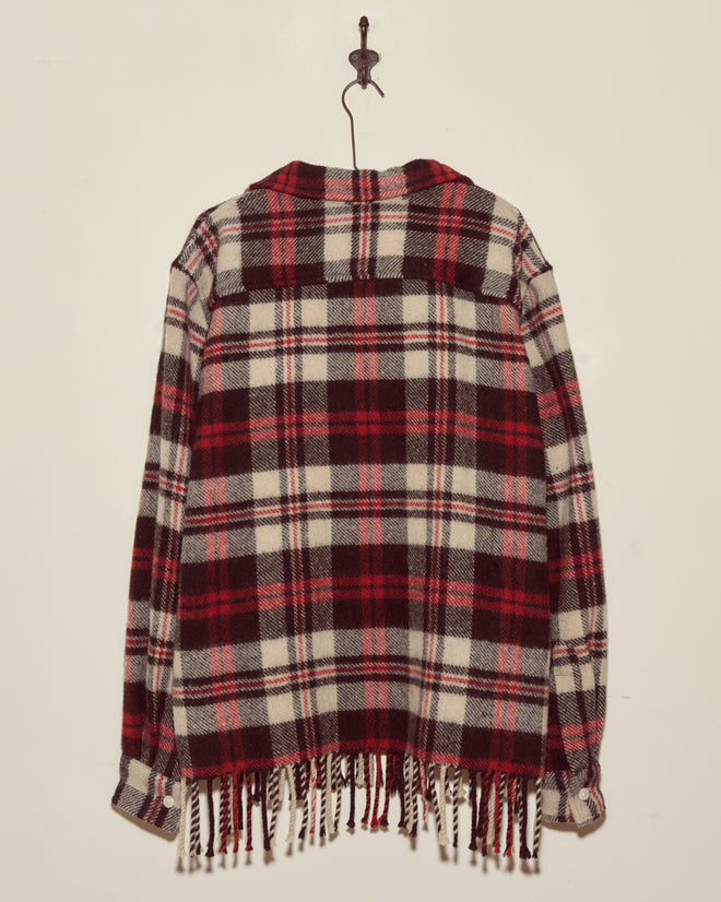 The Collegiate Buffalo Overshirt - XXL, featuring a red, black, and white plaid vintage wool design with fringe, hangs on a star-shaped hook against a plain wall.