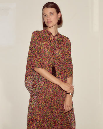 Woman wearing the Confetti Floral Kaftan stands against a plain wall, looking at the camera with a neutral expression.
