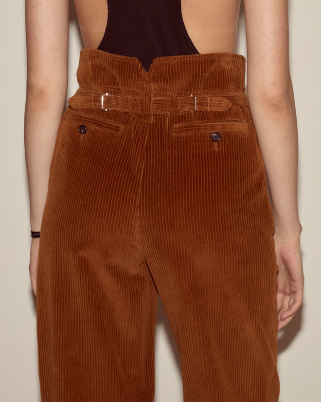 Person wearing Corduroy Shakey Trousers - Brown, featuring a high-rise and wide-leg design, paired with a black open-back top, seen from behind.