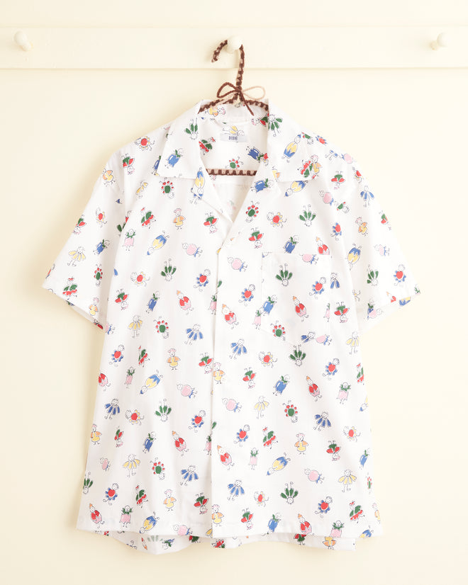 The Costume Buddy Shirt - L/XL is a white short-sleeve button-up shirt crafted from deadstock fabric, featuring a vibrant floral and animal print pattern. This unique piece is displayed on a wall hook.