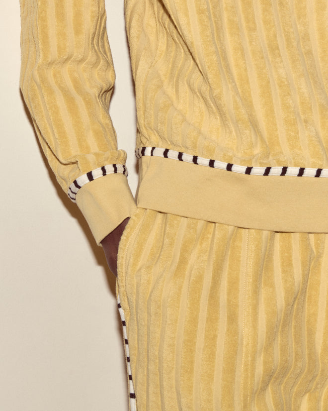 Person wearing a yellow striped velour tracksuit with white and black trim, styled effortlessly over the Croquet Ground Pullover.