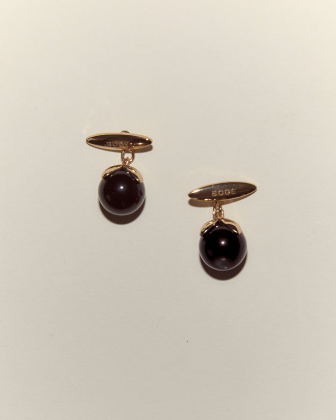 Curio Cufflinks - Black: Gold Victorian Revival cufflinks featuring dark round stones on a plain, light background.