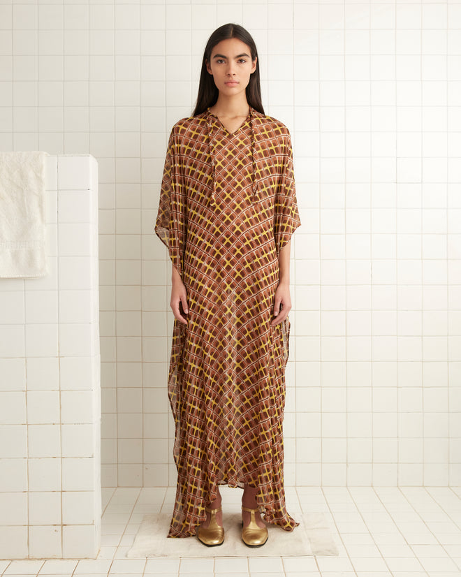 A person wearing the Cattail Plaid Kaftan stands in a tiled room with white walls.