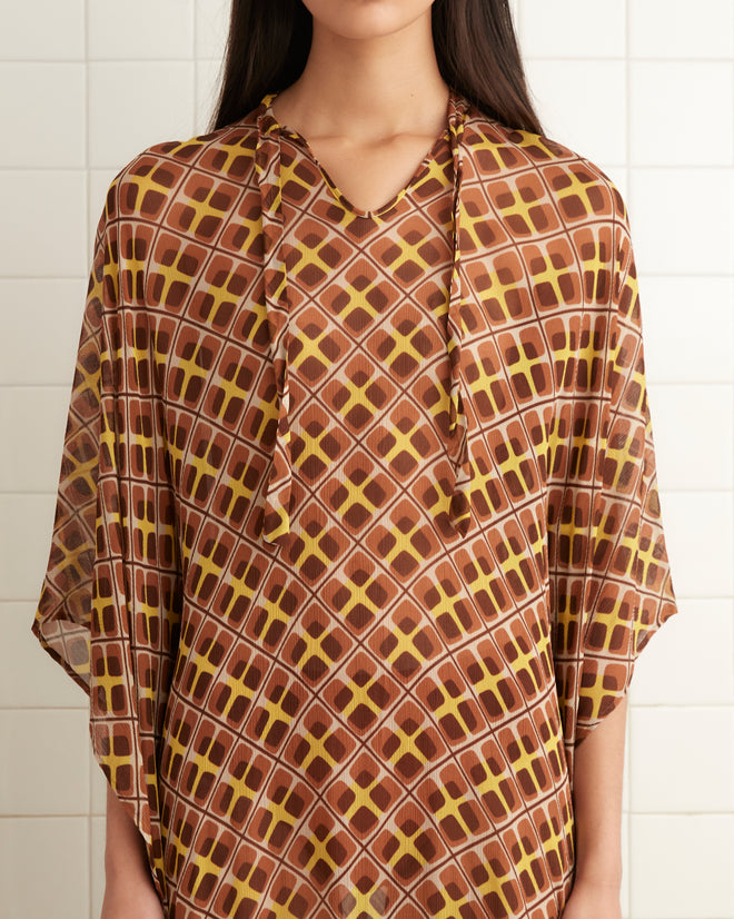 A person wearing the Cattail Plaid Kaftan stands in a tiled room with white walls.