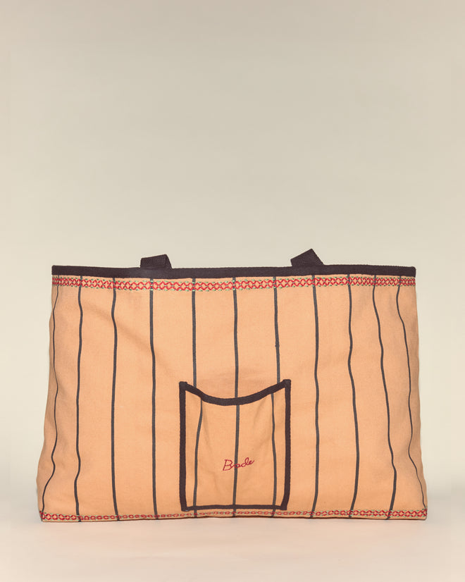 The Cockatoo Large Tote is a beige canvas bag with vertical black stripes, a small front pocket, and two short handles—ideal for everyday use.