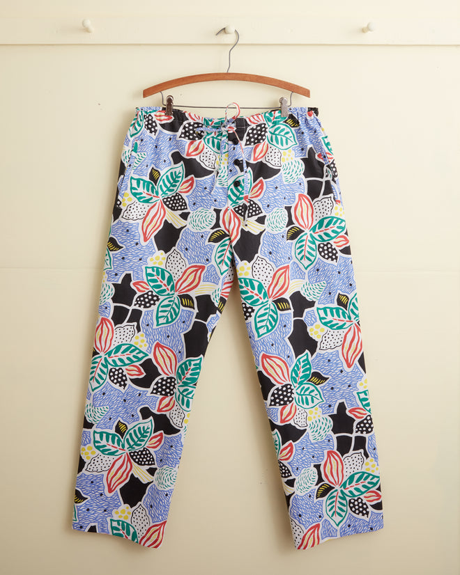 The Plantain Jazz Pajama Pants - M features a unique botanical pattern with abstract leaves, hanging on a wooden hanger against a beige background.