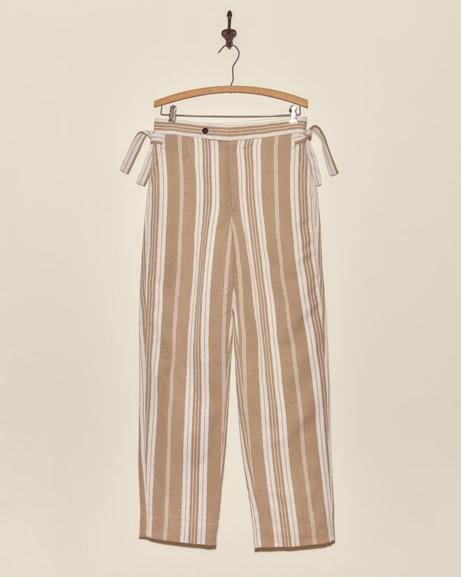 Desert Stripe Trousers - 30: Beige and white vertical striped vintage trousers with side ties, displayed on a wooden hanger against a plain wall.