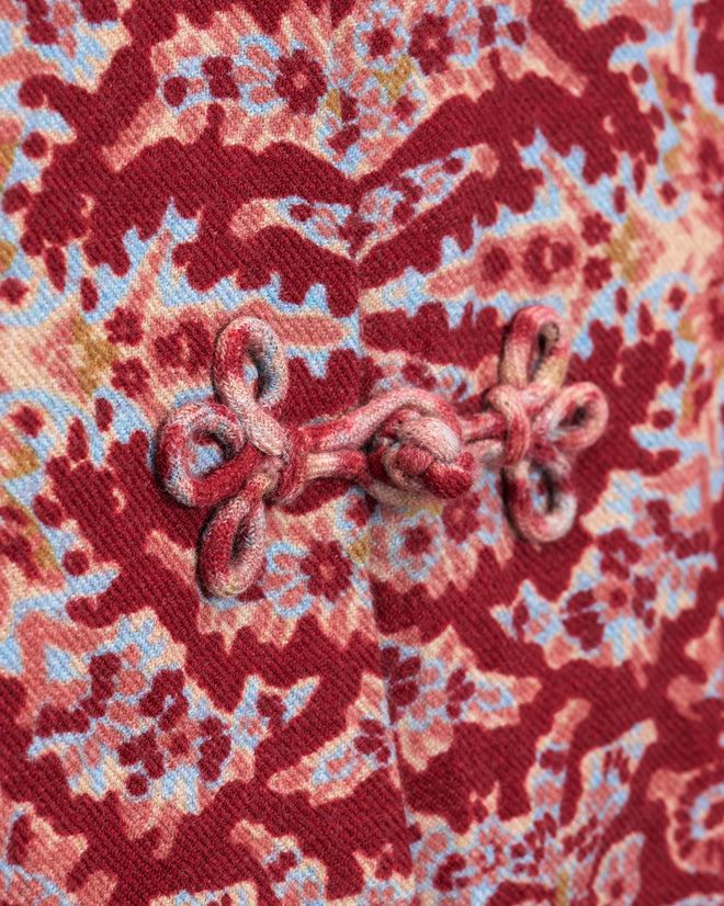 Close-up of the Arrowleaf Blouse, crafted from red patterned fabric reminiscent of Kashmiri shawls and featuring a traditional Chinese frog button closure.