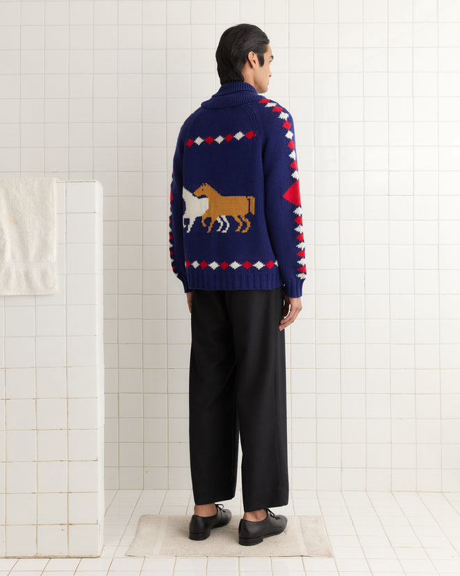 Person in a Diamond Corral Cardigan and black pants stands in a tiled room, facing away.