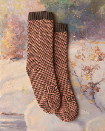 Duotone Jacquard Socks in peach and grey, set against a textured, painted background with floral details, capture the charm of birdseye jacquard.