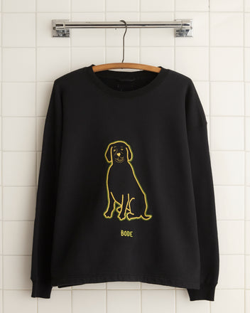 The Embroidered Dog Crewneck, a black 100% cotton sweatshirt featuring a yellow chain-stitch embroidered outline of a dog and the word 