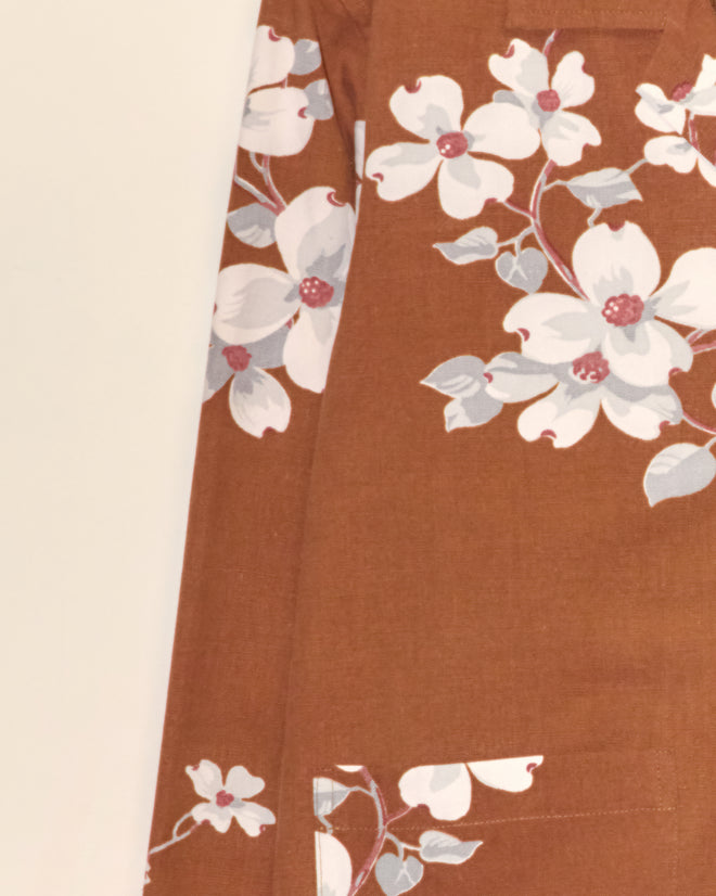 The Dogwood Bark Long Sleeve Shirt - XS features brown fabric with a white and pink floral pattern, showcasing large flowers and greenish-blue leaves for a timeless vintage charm.