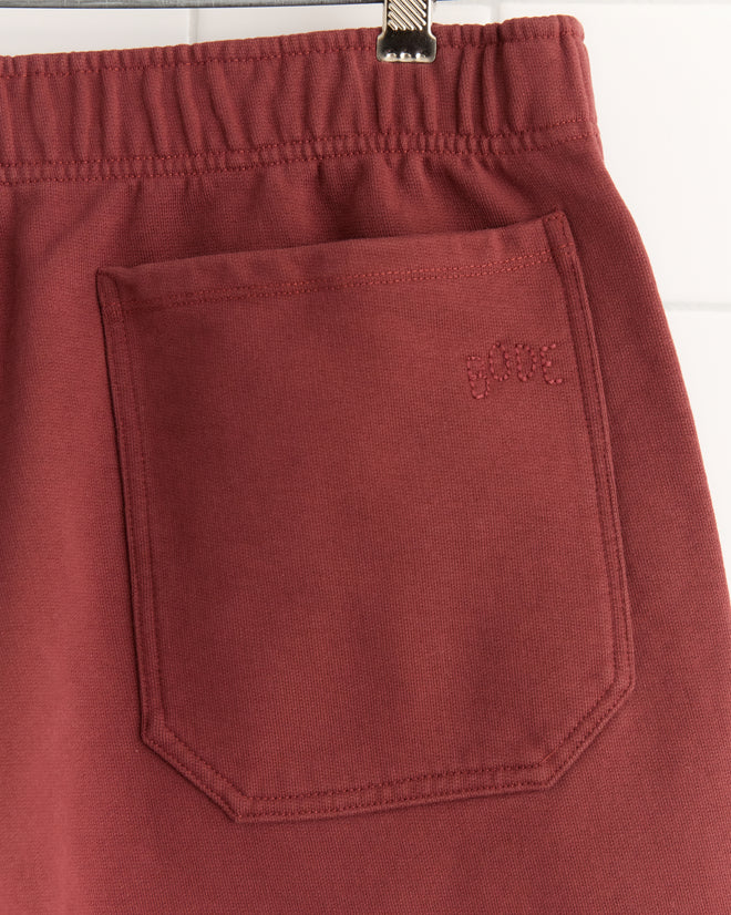 Close-up of a maroon fabric pocket with "babe" embroidered above it, featured on Burgundy Pennant Shorts made from 100% cotton with an elastic waistband.