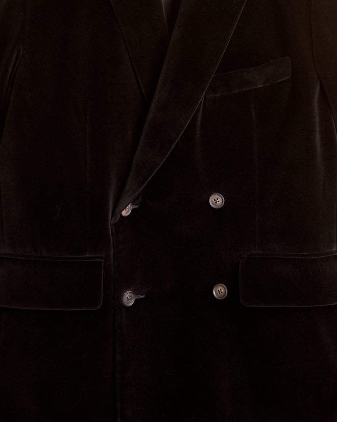 The Dusk Velvet Double-Breasted Suit Jacket for men, evoking the style of the 1950s-1960s, is hanging on a hook against a light-colored wall.