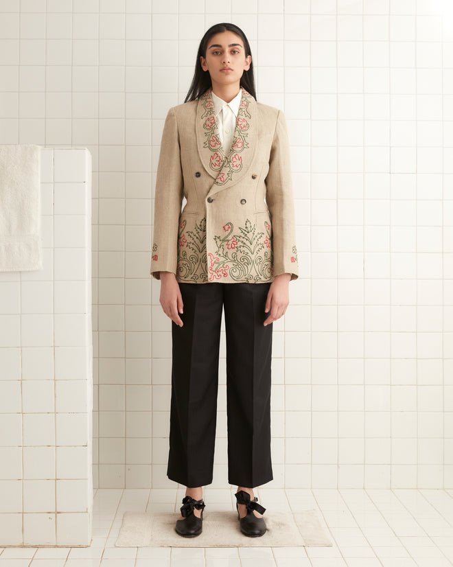 A person wearing an Embroidered Trumpetflower Suit Jacket and black pants stands in a tiled room.