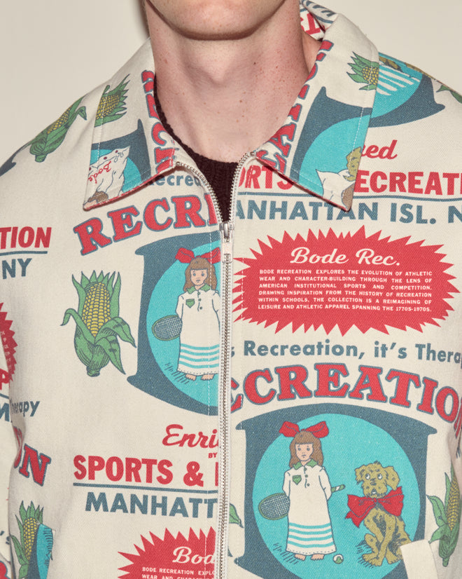 Close-up of a person wearing the Enrichment Jacket, made from 100% cotton and featuring colorful vintage-style graphics and recreation-themed text.