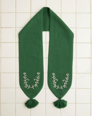 Floret Scarf - Green, crafted from merino wool and featuring embroidered floral designs and tassels, elegantly displayed on a white tiled background.