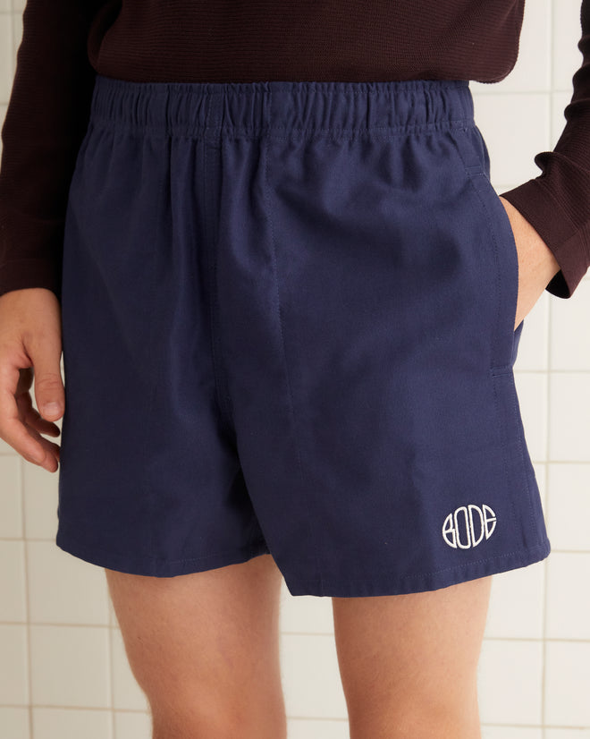 Navy cotton rugby shorts with short inseam and wide leg opening. The shorts are embroidered with a Bode logo.