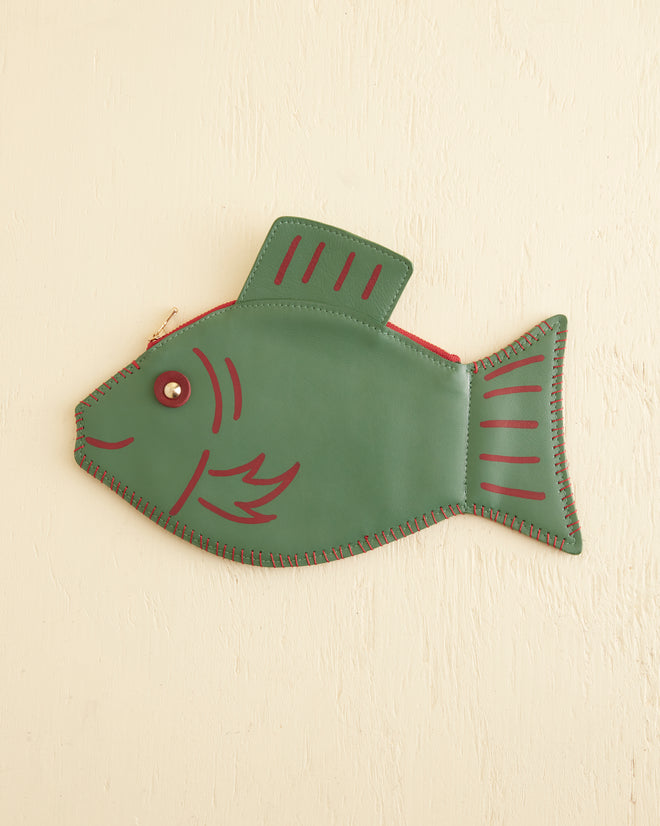 A stylish Fish Clutch, made of green leather with red stitching and details, is beautifully displayed on a beige background.