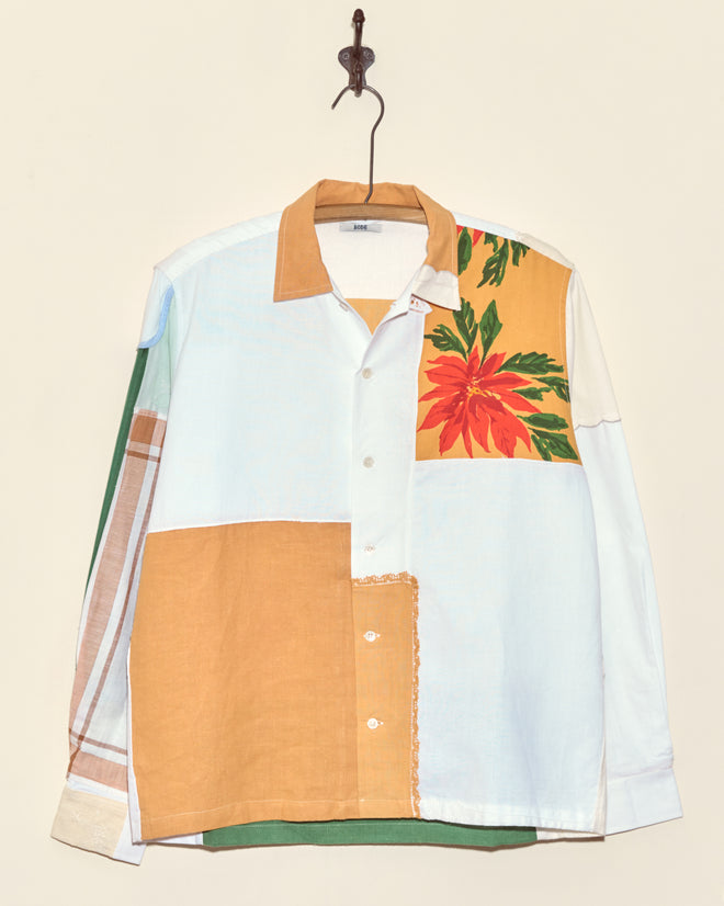 The Flaming Petal Napkin Shirt (S/M) is a unique vintage patchwork shirt featuring floral patterns in white, tan, green, and prints. Displayed on a hanger, this standout piece adds charm and character to any wardrobe.