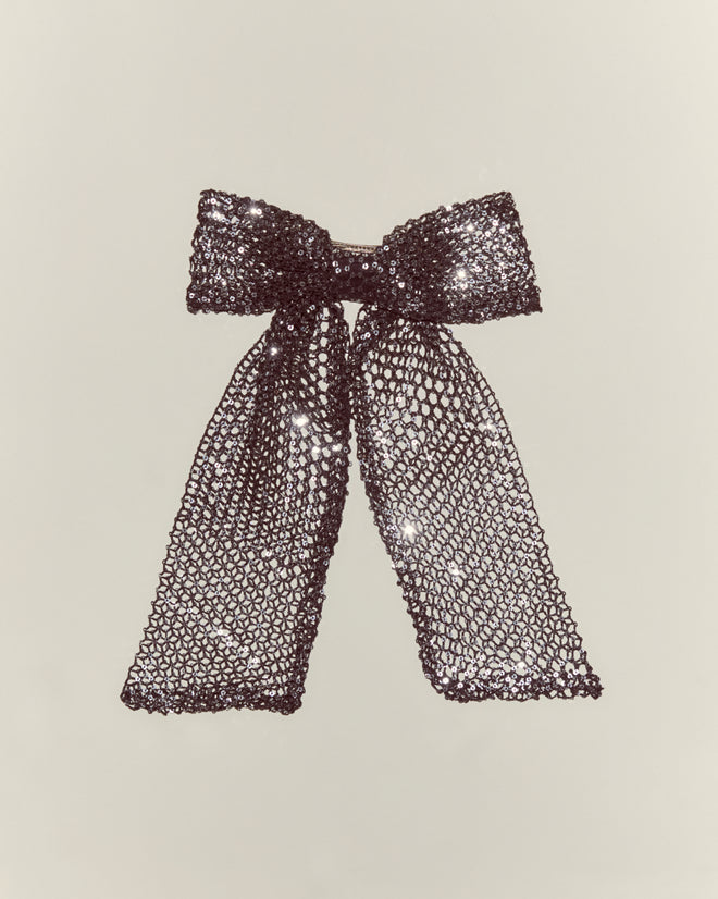 The Tanglenet Bow Barrette features sparkling silver sequins and long tails, inspired by 1930s style, displayed against a plain light background.