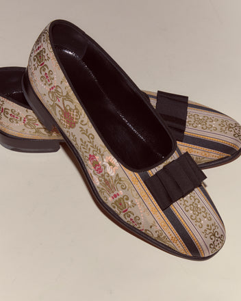 The Floret Brocade Opera Pumps are men's evening slippers inspired by the Bode Opera Pump, featuring black bows and floral and striped designs on a light background, crafted in Italy.