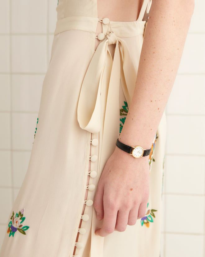 A person wearing the Flower Language Dress, featuring floral embroidery and fringe, stands against a tiled wall.