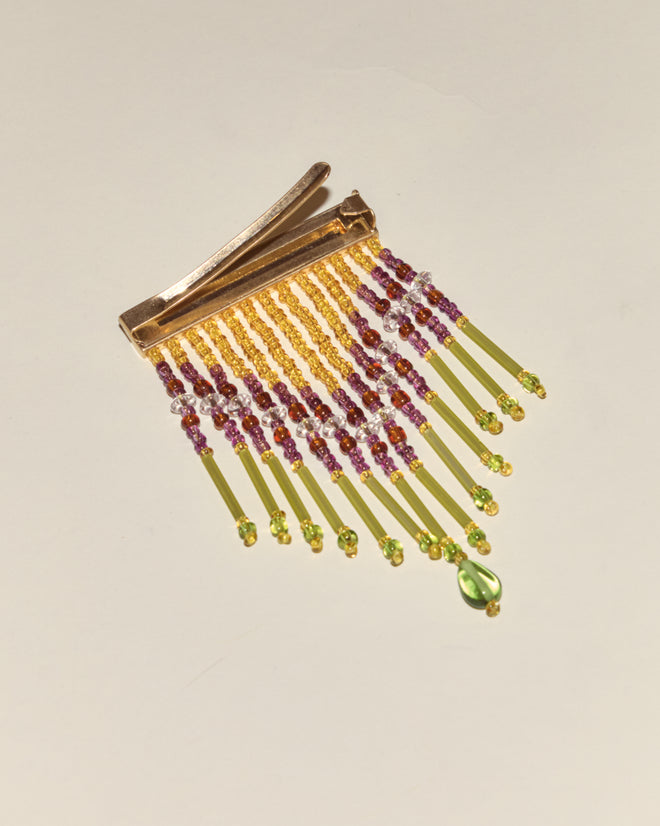 The Fringe Barrette - Gold features gold beading with dangling yellow, purple, and green strands, each tipped with a green teardrop bead.