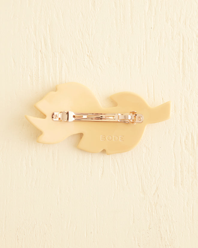 The Frond Barrette is a cream-colored, leaf-shaped accessory featuring intricate textured leaf details on a light background, capturing the nostalgic charm of Bakelite in a soft butterscotch shade.