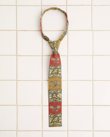 A Tennis Court Necktie featuring a 1960s pattern with sections of red and gold lies on a tiled white surface.