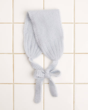 A chic light blue knitted headband is elegantly laid out on a white tiled surface, showcasing the ultimate in luxurious accessories.