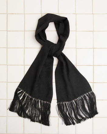 The elegant Football Jacquard Scarf - Black, made of luxurious viscose silk with fringe ends, is stylishly laid flat on a tiled white surface.