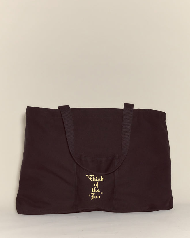 The Geneva Tote is a spacious black canvas bag made of durable cotton, with "Think of the Fun" in yellow script on the front pocket—a perfect Camp Geneva keepsake.