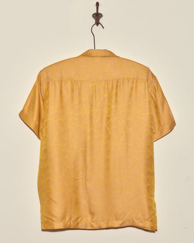 Golden Shell Short Sleeve Shirt—deadstock yellow jacquard button-up, displayed on a hook against a plain beige wall.