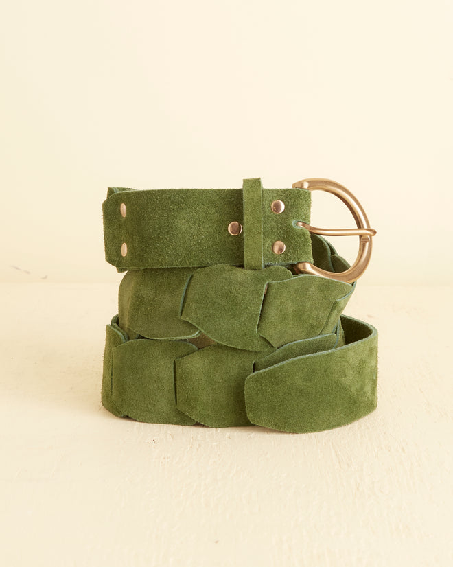 The Suede Link Belt - Green, inspired by '70s fashion, features a woven design crafted from 100% green suede and is adorned with a brass buckle. It is showcased on a light surface.