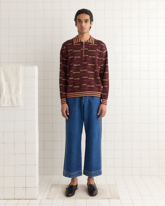 Wearing the Gridiron Quarter-Zip and blue jeans, a person stands on a white bathroom mat against a tiled wall.