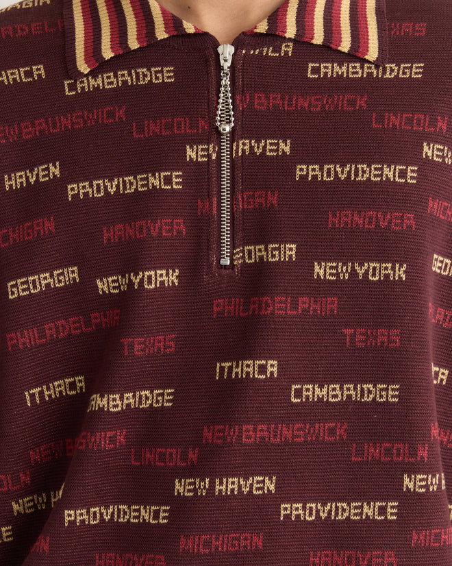 Close-up of the Gridiron Quarter-Zip, a maroon shirt featuring yellow and red city names, a striped collar, and a subtle jacquard pattern.