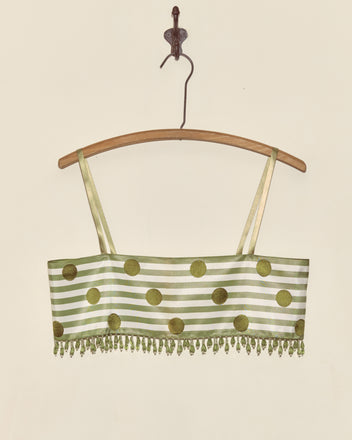 The Green Note Bra - S features green and white stripes with gold polka dots, gold straps, beaded fringe, and Staron jacquard ribbon accents—presented as a unique piece on a wooden hanger.