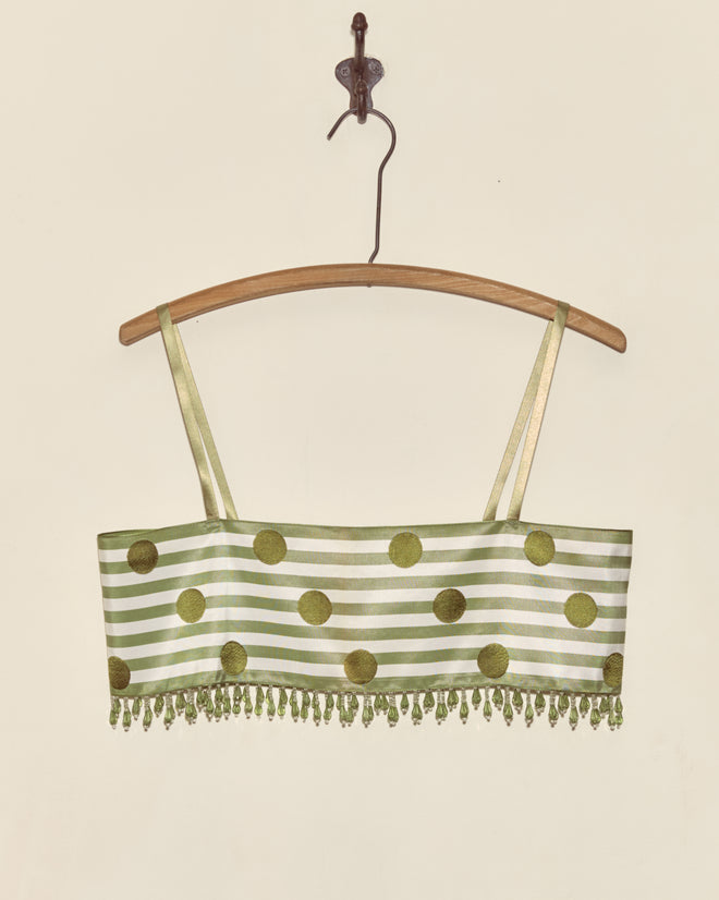 The Green Note Bra - S features green and white stripes with gold polka dots, gold straps, beaded fringe, and Staron jacquard ribbon accents—presented as a unique piece on a wooden hanger.