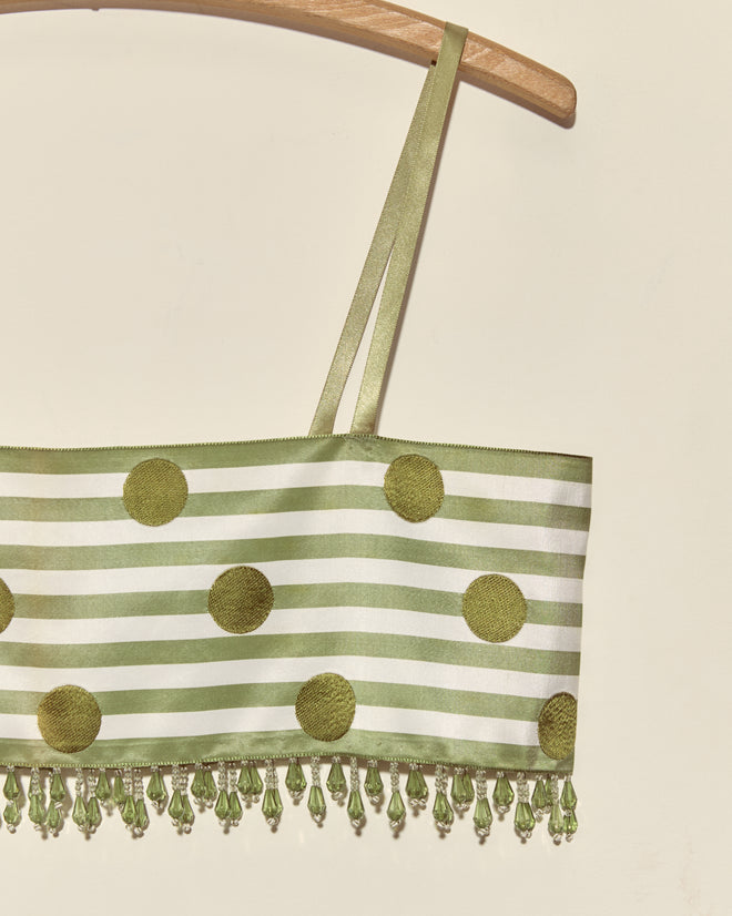 Green Note Bra - S: Green and white striped crop top with large green dots, beaded fringe, and Staron jacquard ribbon details, displayed on a wooden hanger.